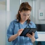 A nurse completes an incident report using a tablet.