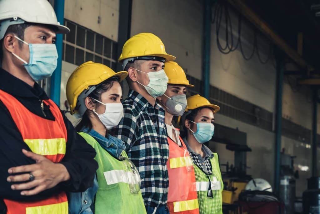 A group of workers proudly displays their use of personal protective equipment.