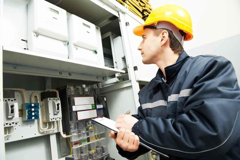 An inspector notes observations tediously on a clipboard. Learn how your team can use your app for a better electrical inspection checklist at 1stReporting.com.