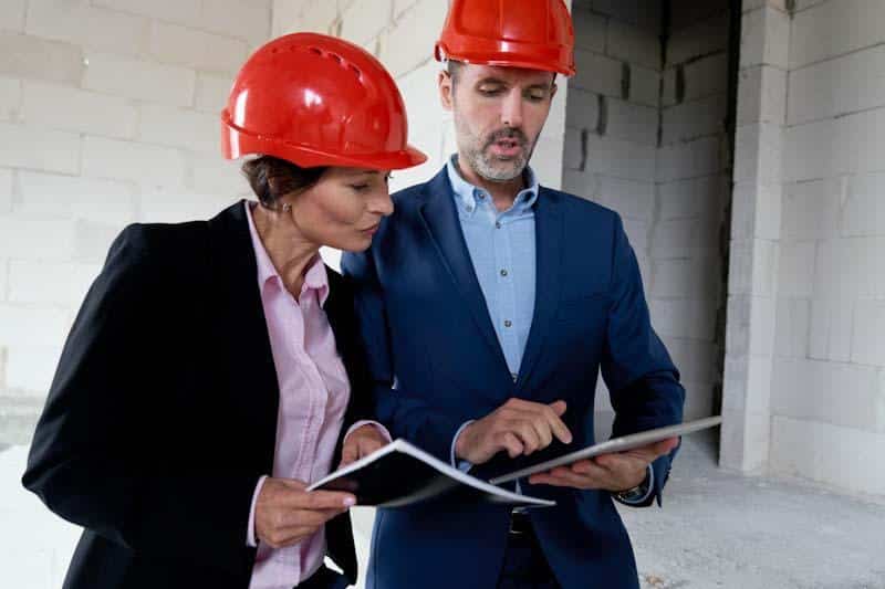 Two managers inspect their new building and review notes from a technical inspection using a tablet with the 1st Reporting application. Learn more at 1stReporting.com.