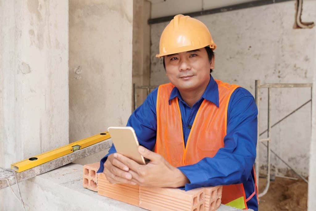 A construction worker happily holds his smartphone.