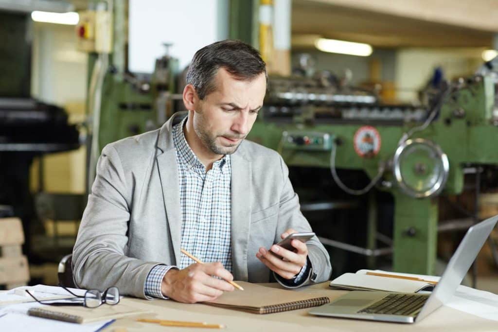 A manager reviews a quality control checklist on his mobile device. Learn more about mobile reporting at 1stReporting.com.