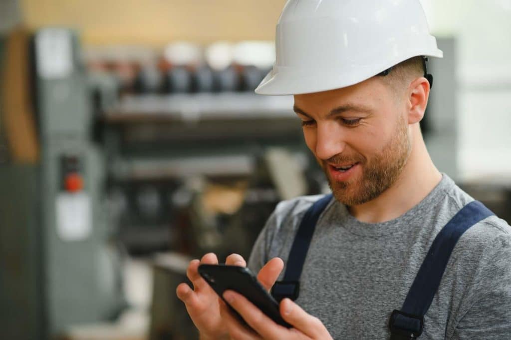 An engineer happily reviews a QC checklist completed on his mobile device. Learn how to make your QC inspections more efficient by using the 1st Reporting app at 1stReporting.com.