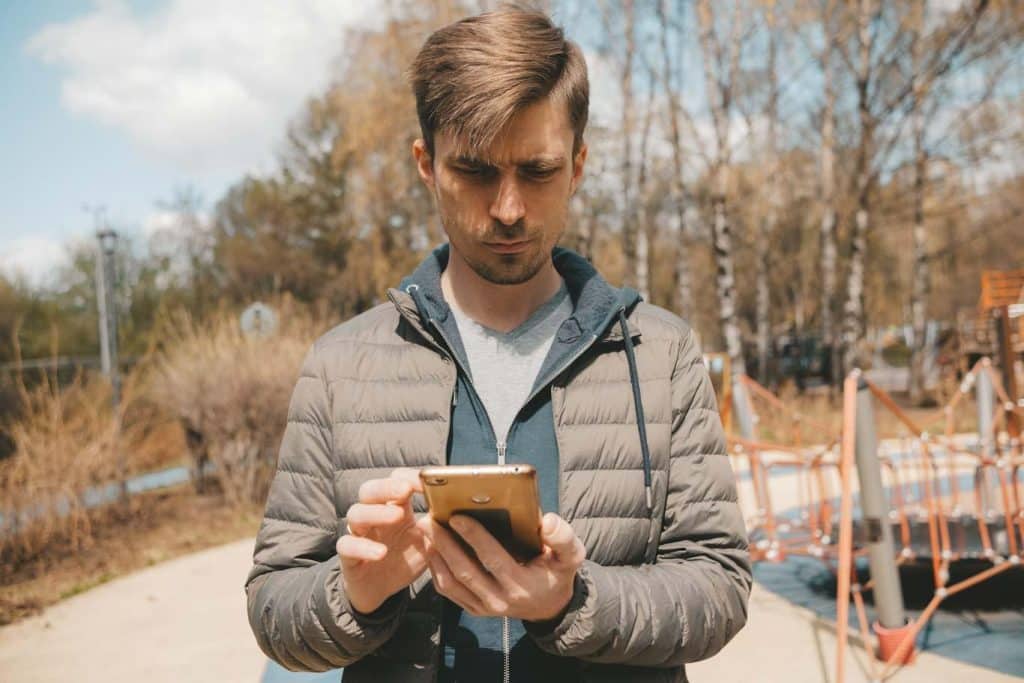 A man completes a playground safety audit form on his smartphone using the 1st Reporting public reporting features. Learn more at 1stReporting.com.